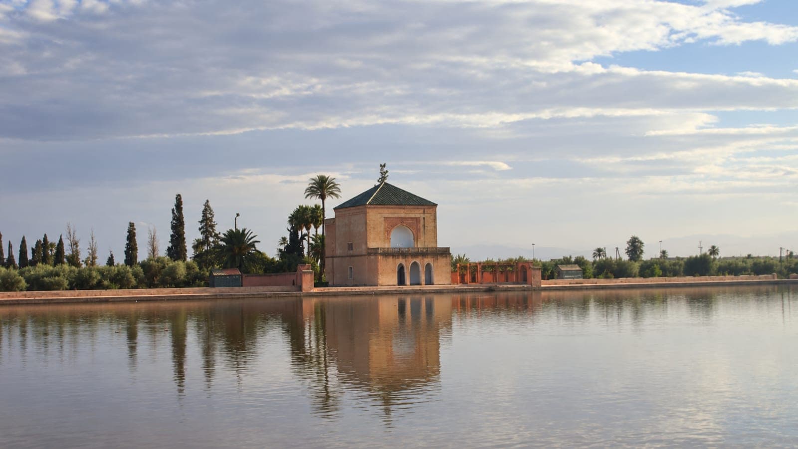 The green-roofed Menara pavilion and its reflection in the reservoir in Marrakech; photograph retouched to remove visitors