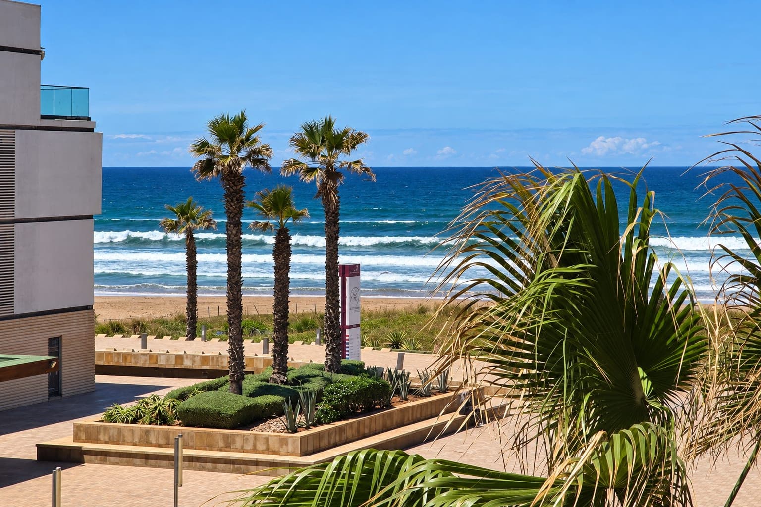 Palms, a seaside promenade and breaking waves in Morocco; owner photograph retouched to remove people